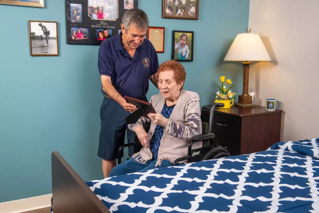 woman in wheelchair and man looking at framed photo